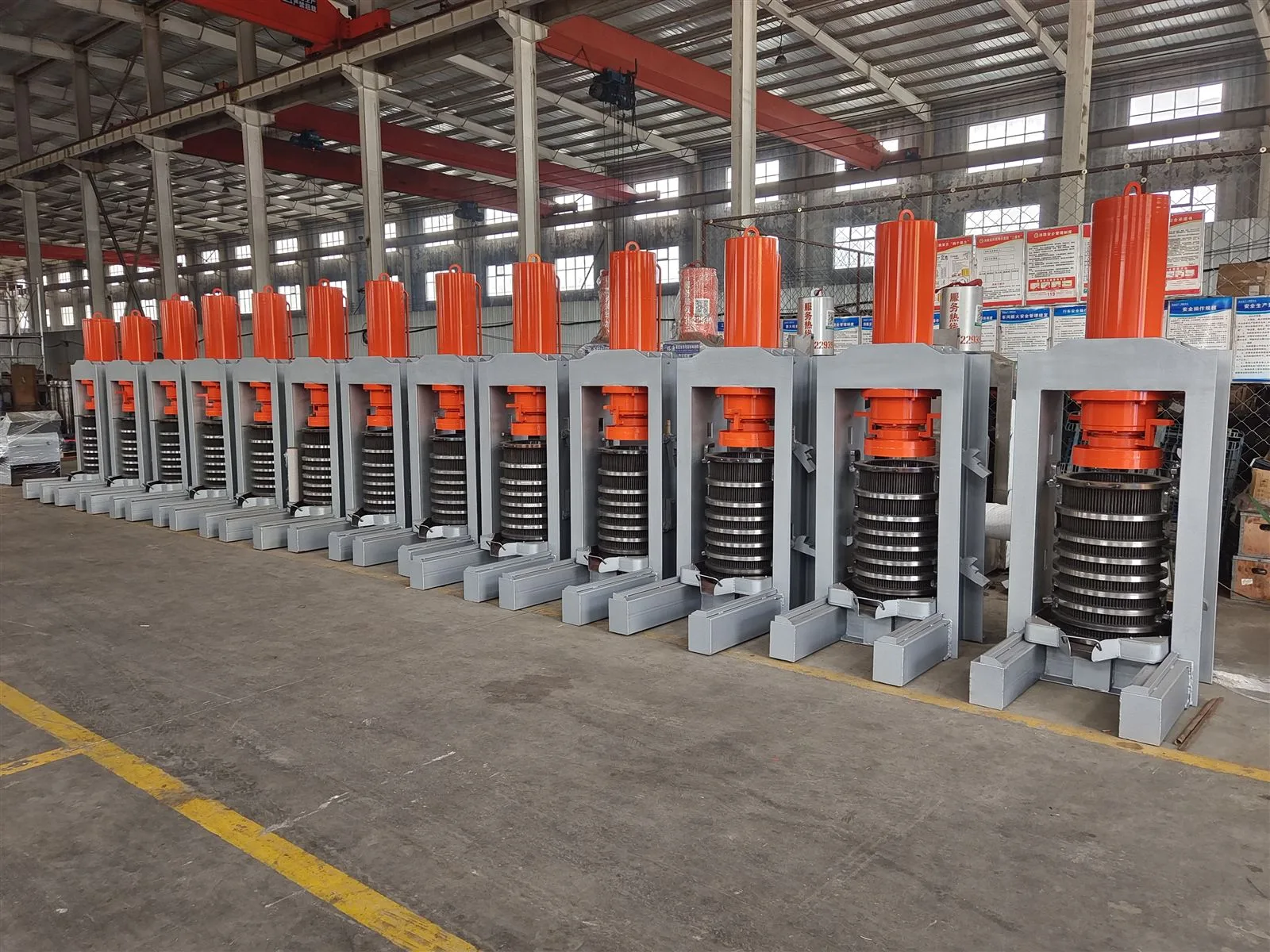 Row of finished orange-cylinder hydraulic oil presses
